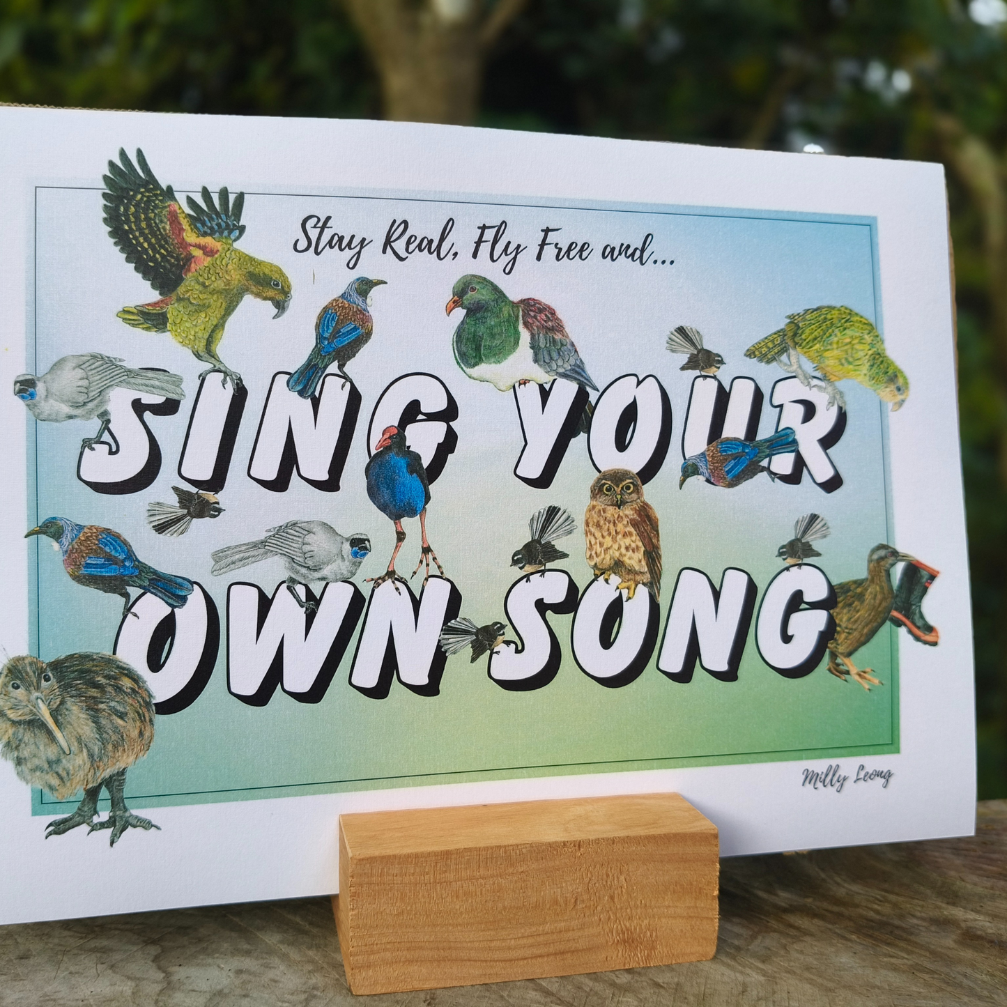 A4 art print with birds and motivational text 'Stay Real, Fly Free and Sing Your Own Song' on a stand.