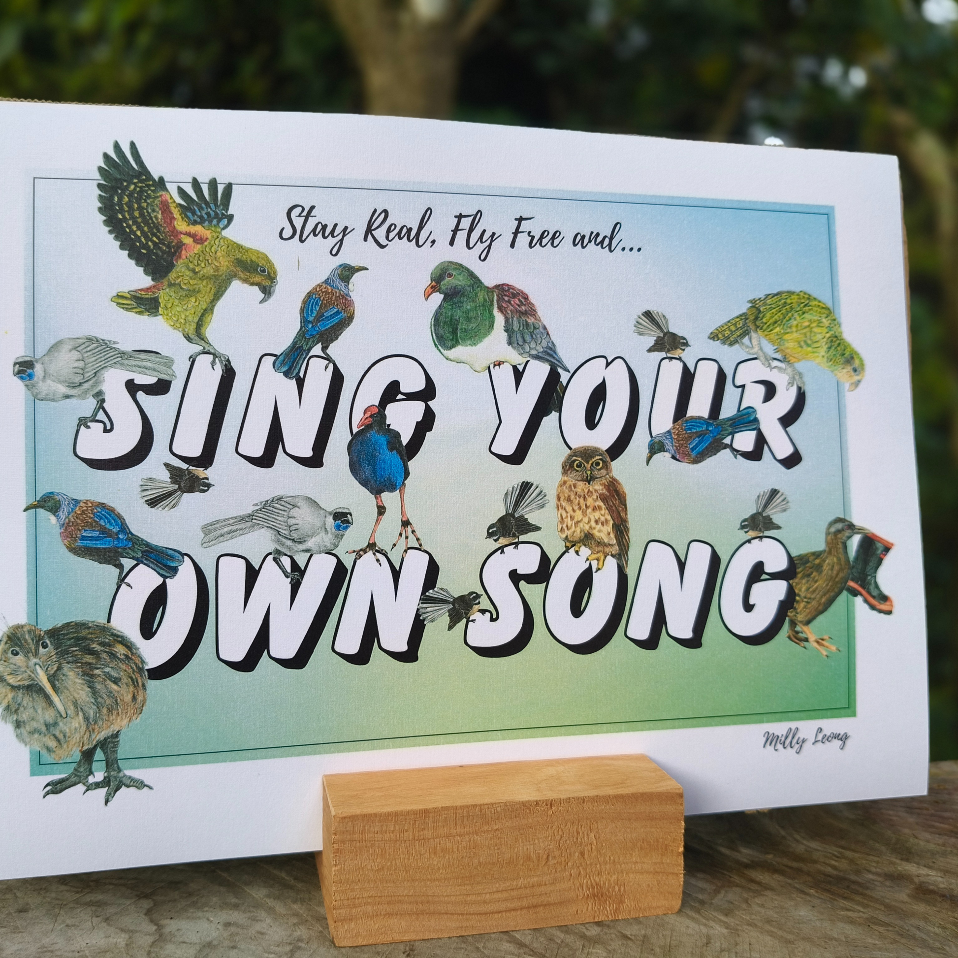 A4 art print with birds and motivational text 'Stay Real, Fly Free and Sing Your Own Song' on a stand.