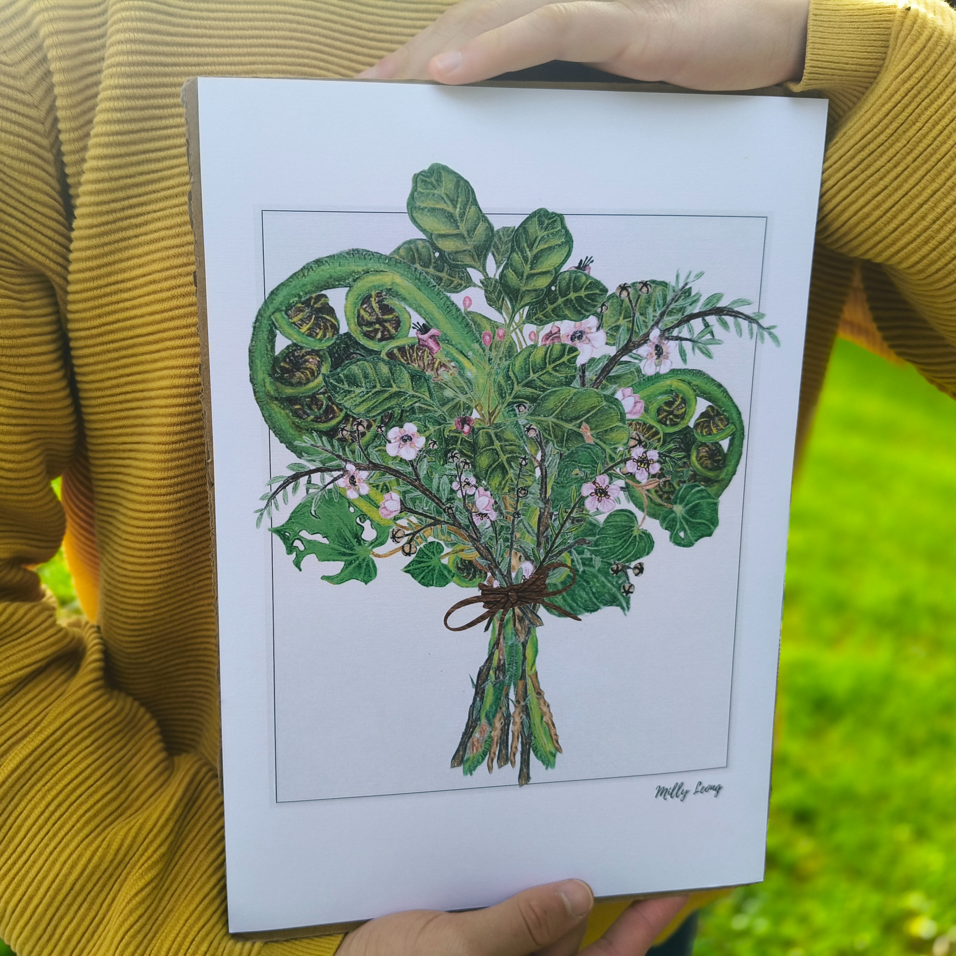 Person holding a print of a green bouquet of native NZ flora.