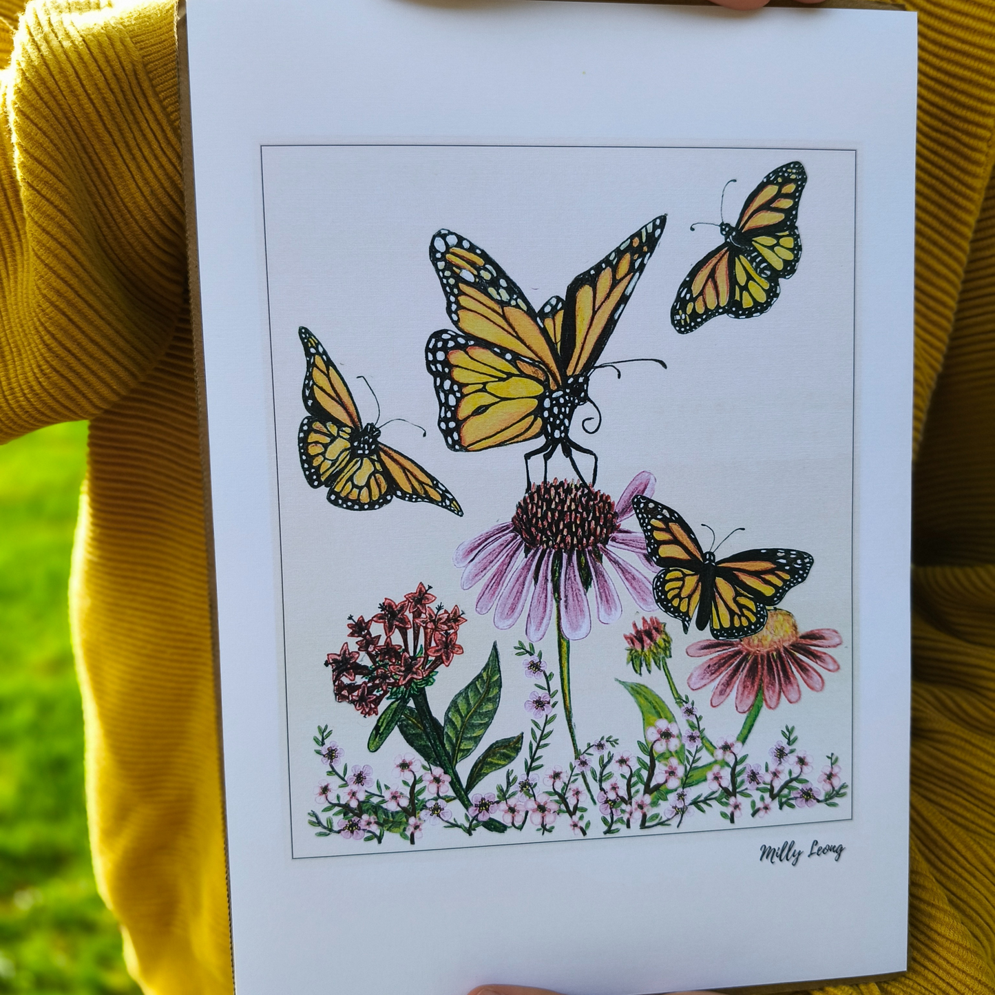 Illustration of butterflies and flowers held by a person wearing a yellow sweater.