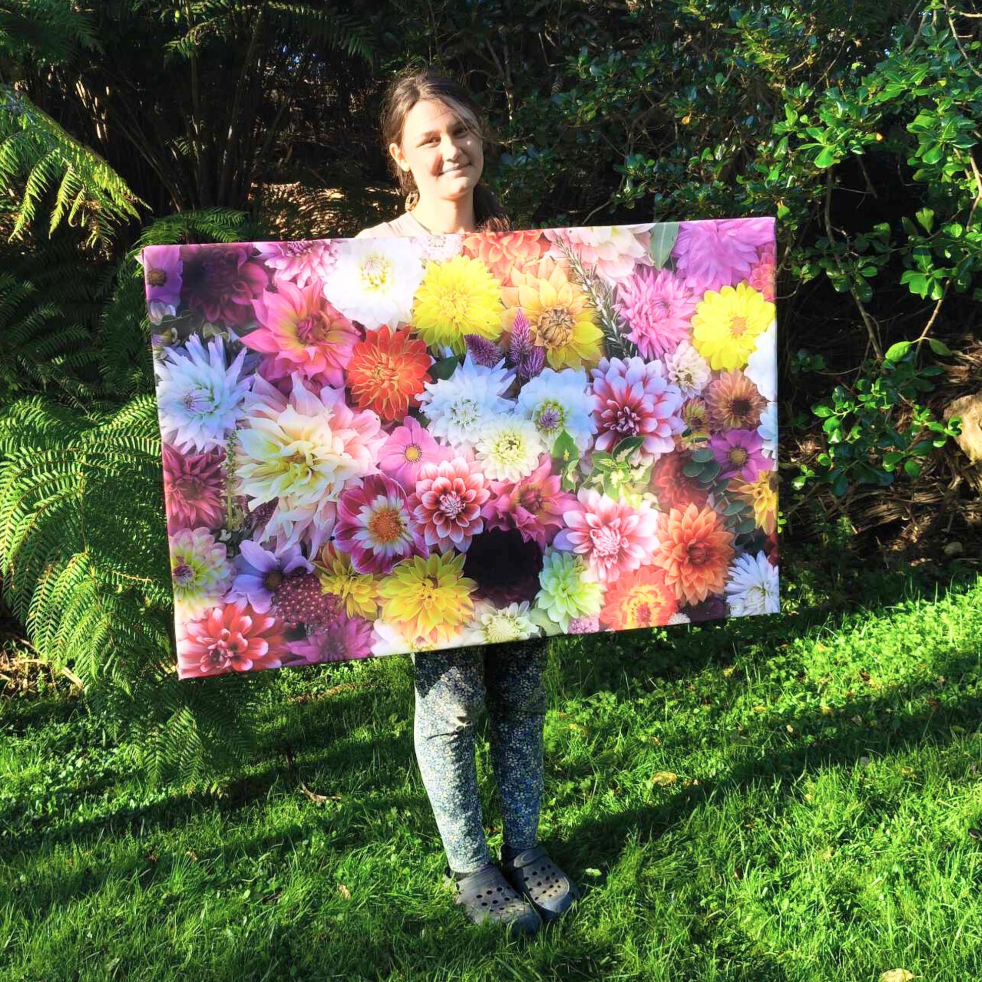 Gracie-Mae holding one of her canvases called Mixed Dahlia Delight.