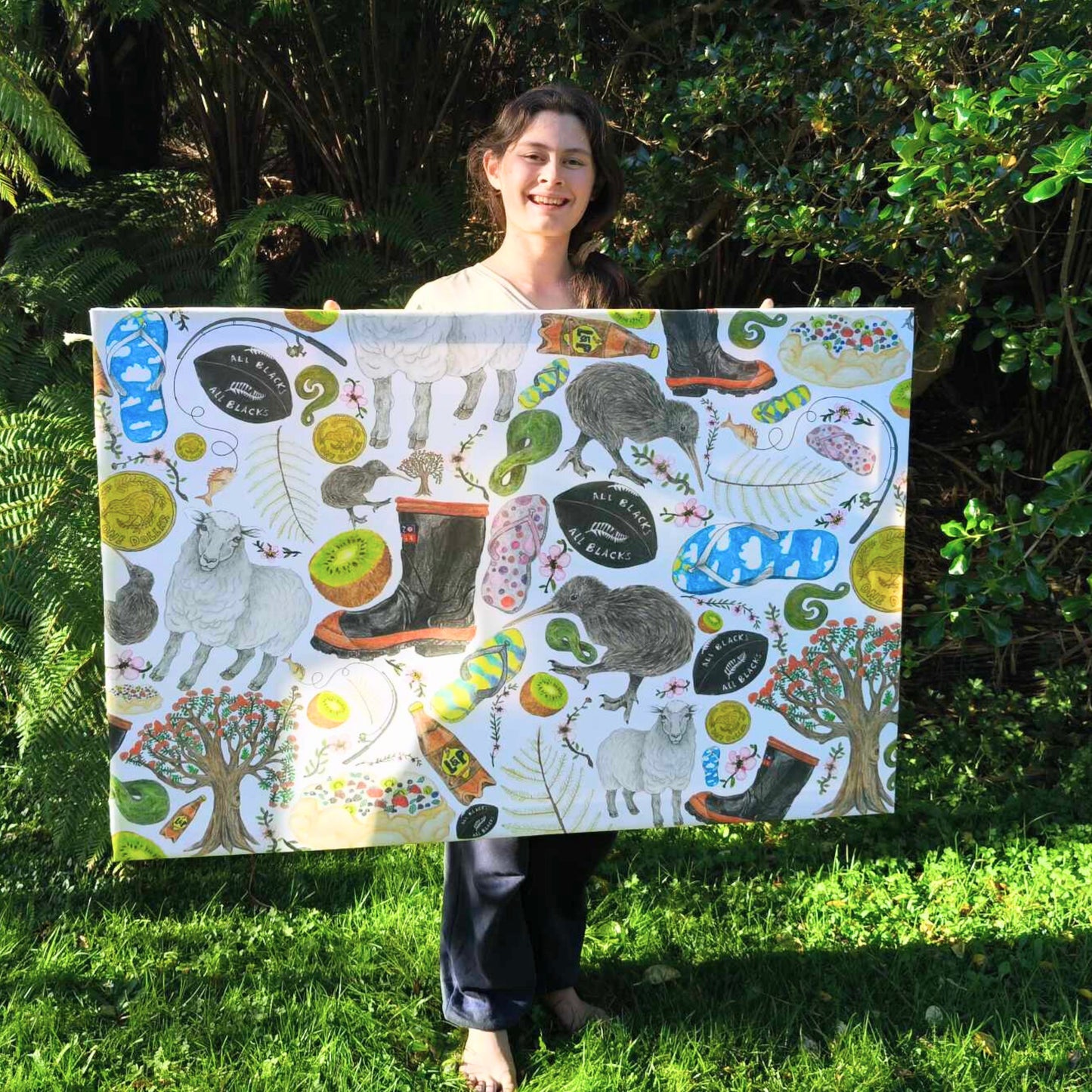 Milly holding her New Zealand Kiwiana canvas in front of NZ bush.