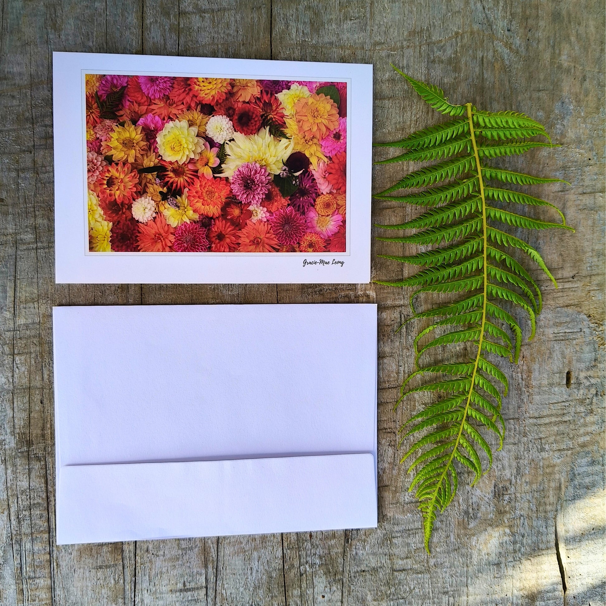Greeting card featuring bright orange dahlia flatlay by Gracie-Mae – blank inside